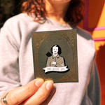 Someone holding the Poes Before Hoes Edgar Allan Poe Enamel Pin in front of themselves.