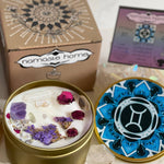 The Gemini Crystal Candle opened with the lid to the right of it. The packaging of the Gemini Crystal Candle is behind the candle next to a card