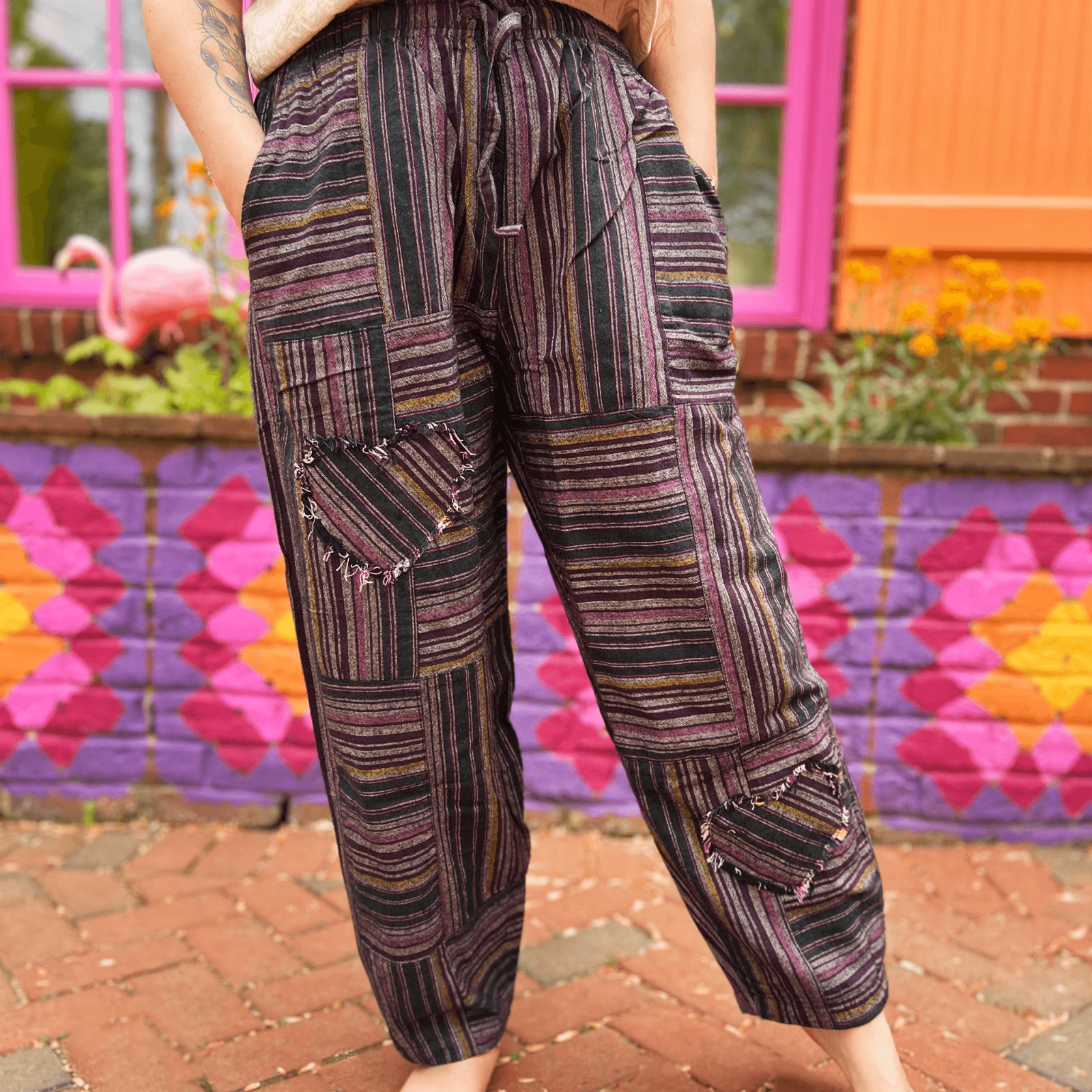 Person wearing patterned pants standing in front of a colorful mural.