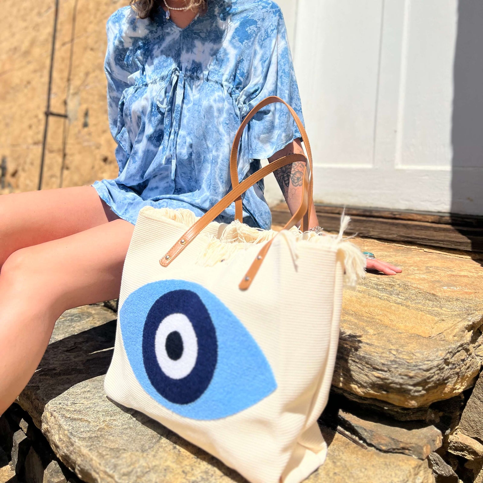 Woman carrying boho evil eye tote bag outdoors in casual outfit
