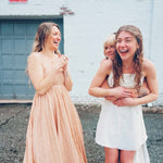 cute boho dresses in front of white brick