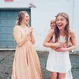 cute boho dresses in front of white brick