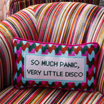 Funny needlepoint pillow styled on a chair with colorful retro disco decor