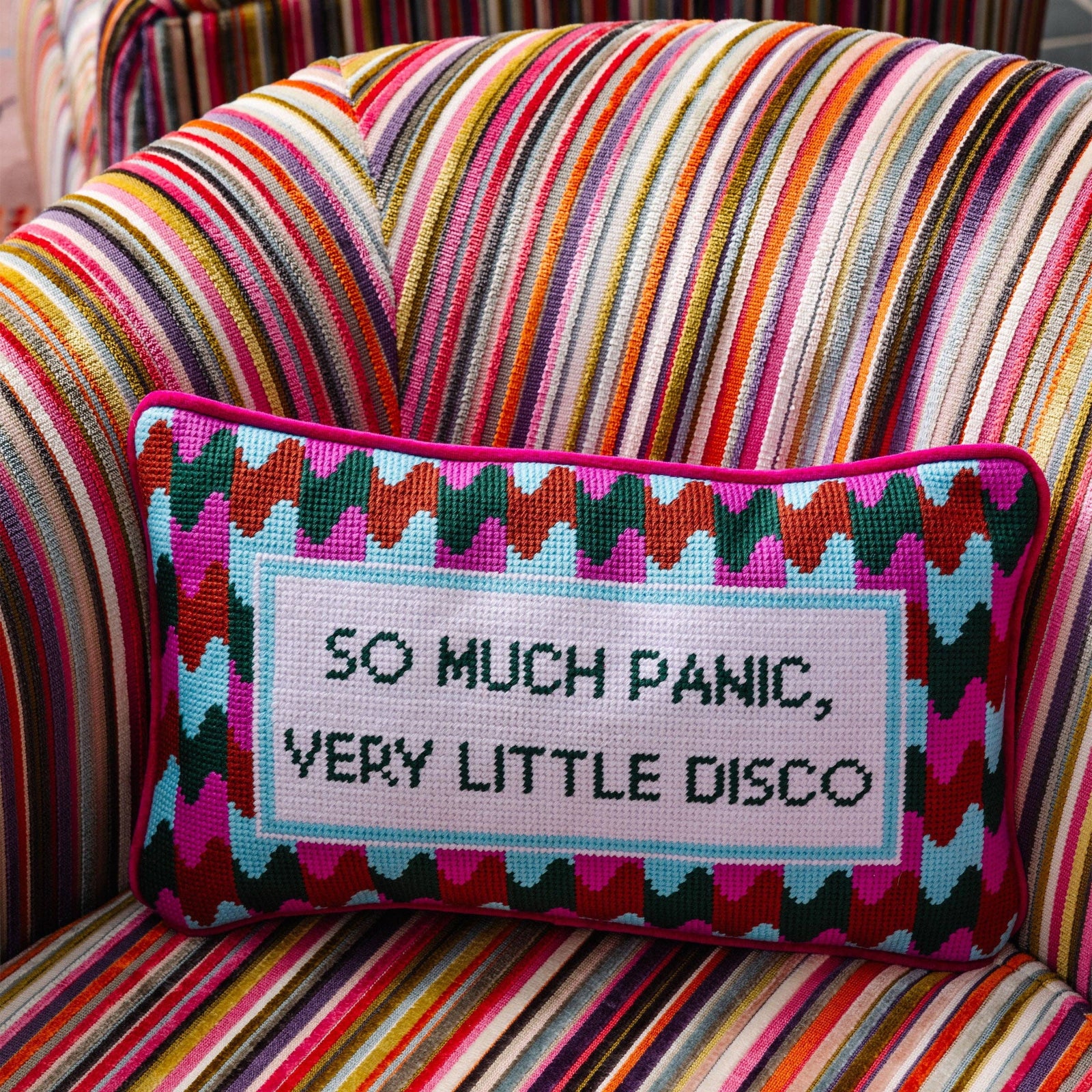 Funny needlepoint pillow styled on a chair with colorful retro disco decor