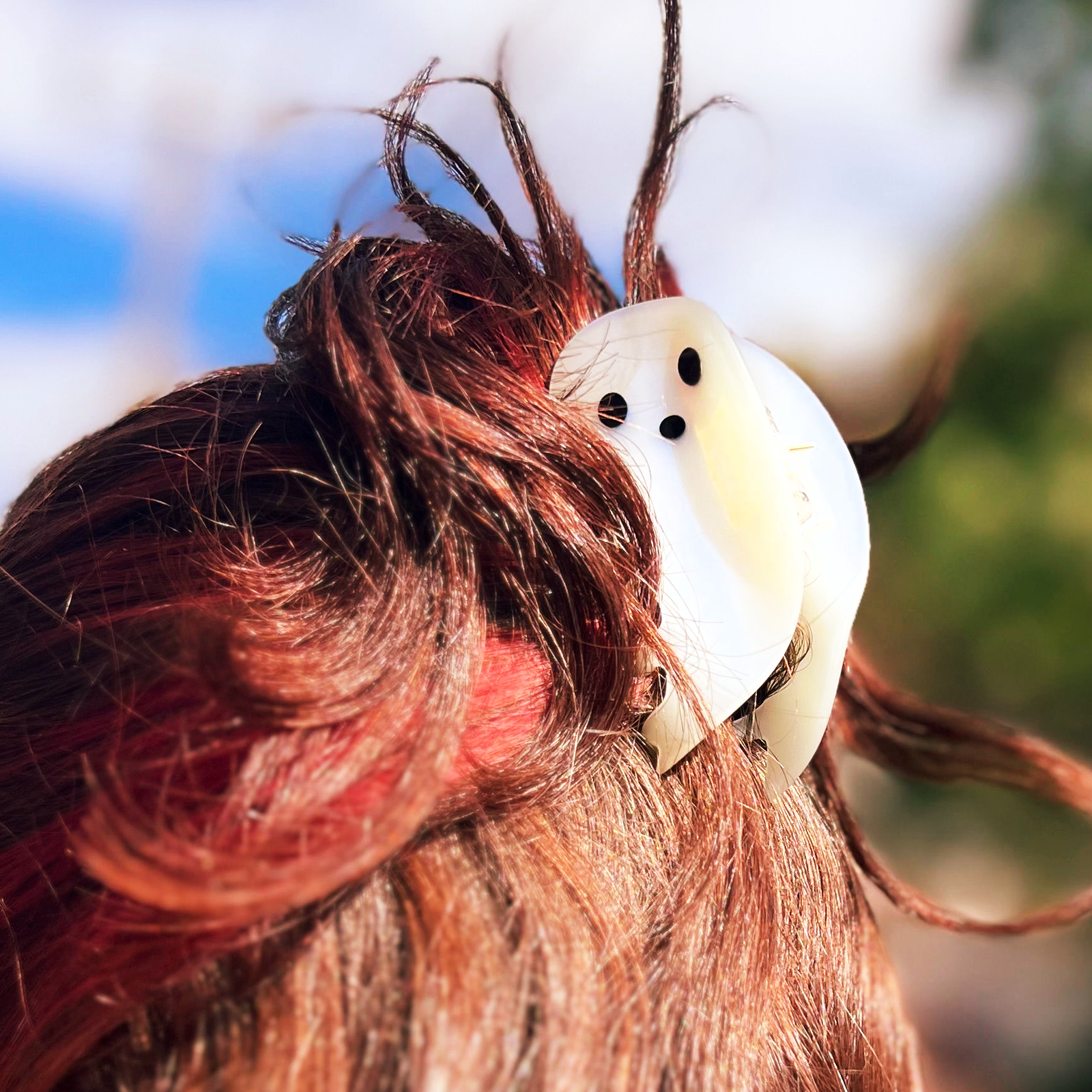 Someone with red and brown hair wearing the small Ghost Claw hair clip.