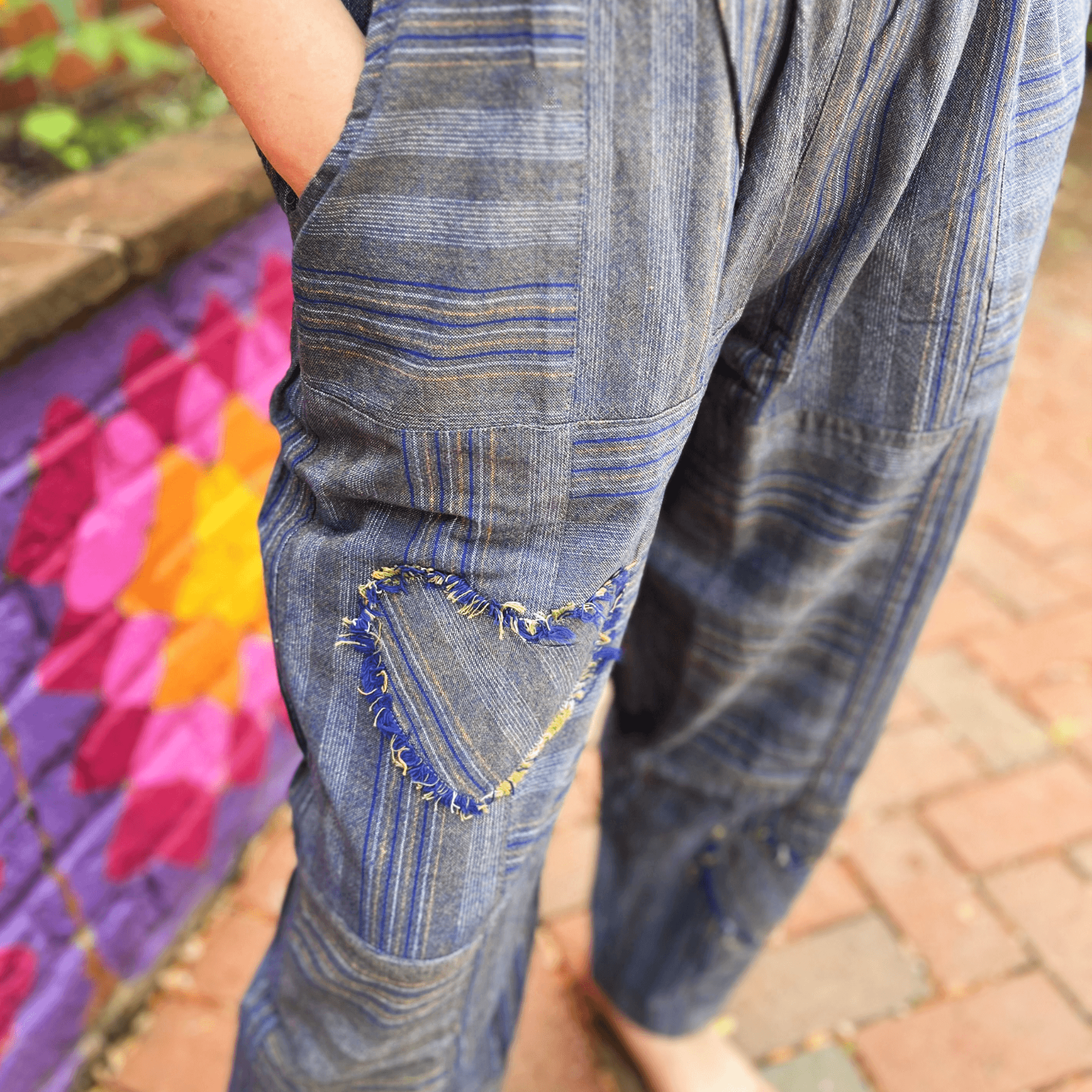 Close-up of heart patch detail on striped boho patchwork pants with raw edge stitching