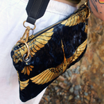 Someone wearing the Small Black and Gold Heron Velvet Crossbody Bag with a white skirt.