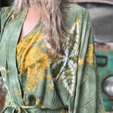 Person wearing a green and yellow patterned robe with a blurred background
