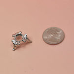 Silver sphere stand with decorative design next to a penny on a beige background