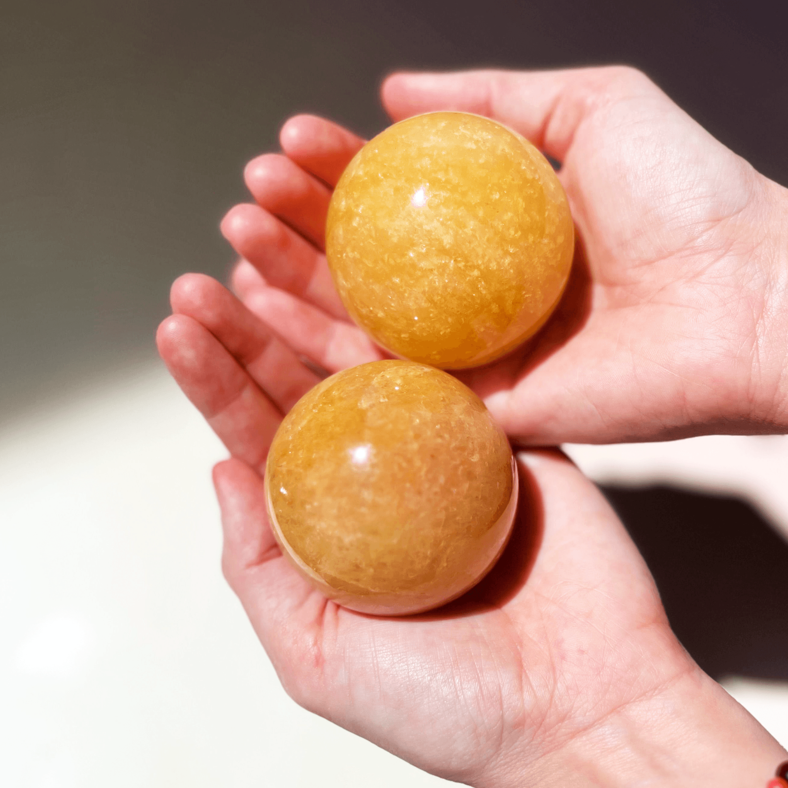 bright orange calcite sphere in hand glowing citrus crystal