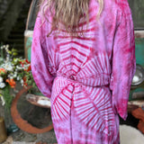 Person wearing a pink tie-dye kimono in front of a vintage vehicle.