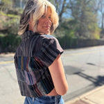 model looking over her shoulder with blonde hair and showing a side view of the cropped blouse