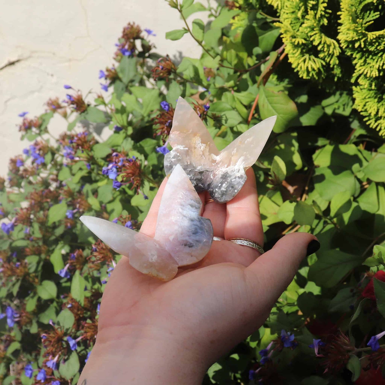 Two pink agate crystal butterflies in hand with natural patterns
