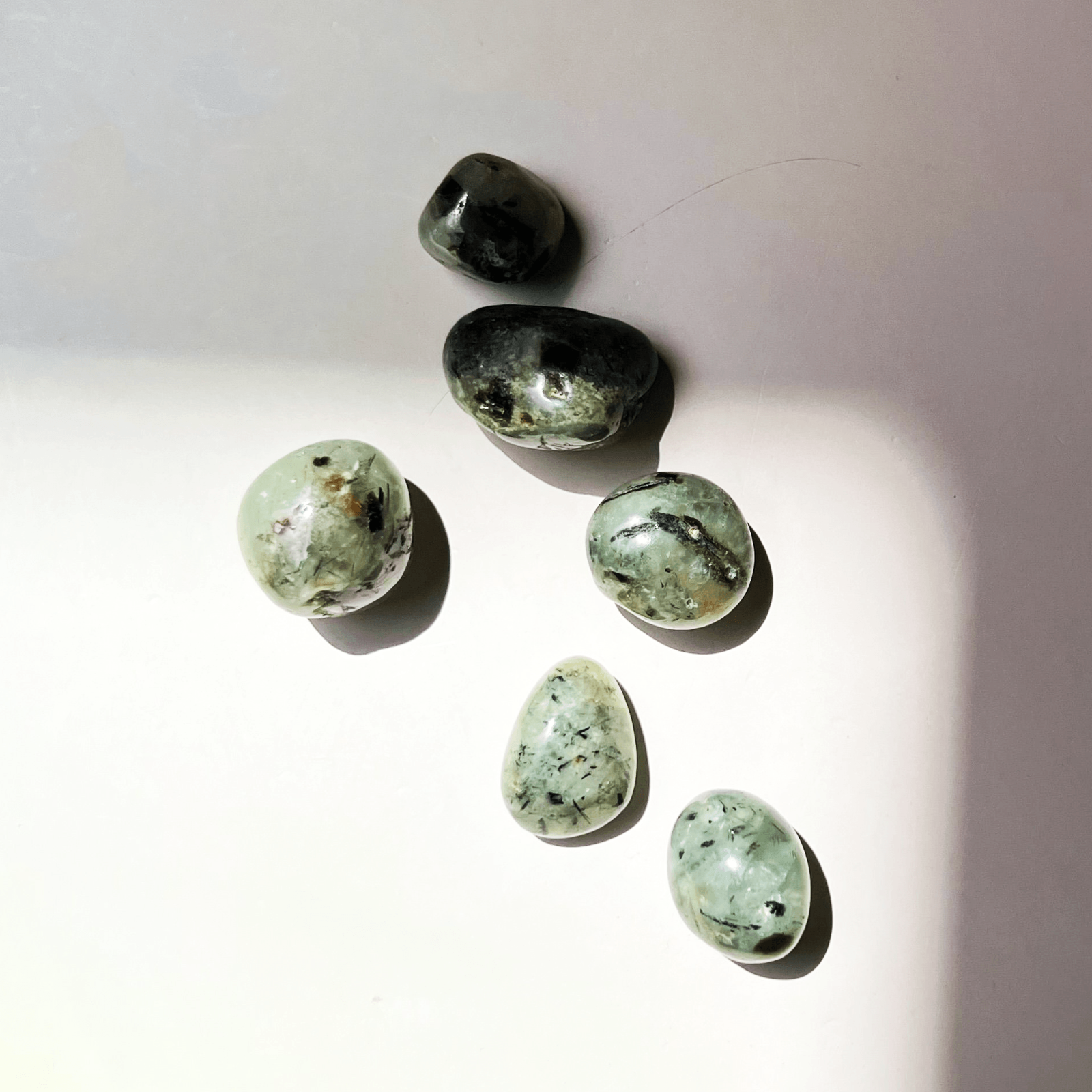 Close up of prehnite crystal tumble showing translucent green color and natural inclusions
