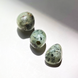 Natural prehnite crystal tumbles with soft green tones and black inclusions polished stones