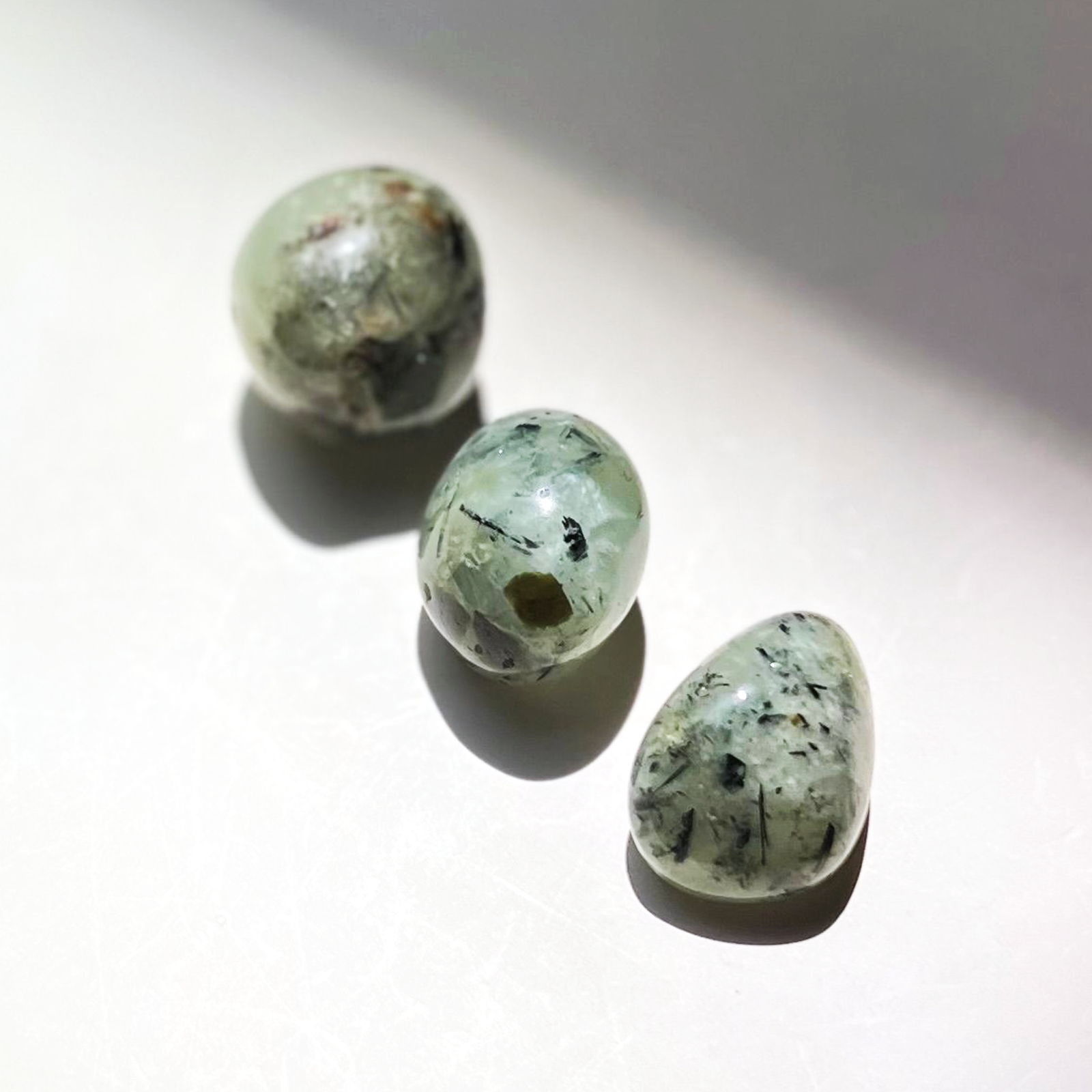 Natural prehnite crystal tumbles with soft green tones and black inclusions polished stones