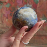 Hand holding a blue kyanite sphere showcasing the crystal