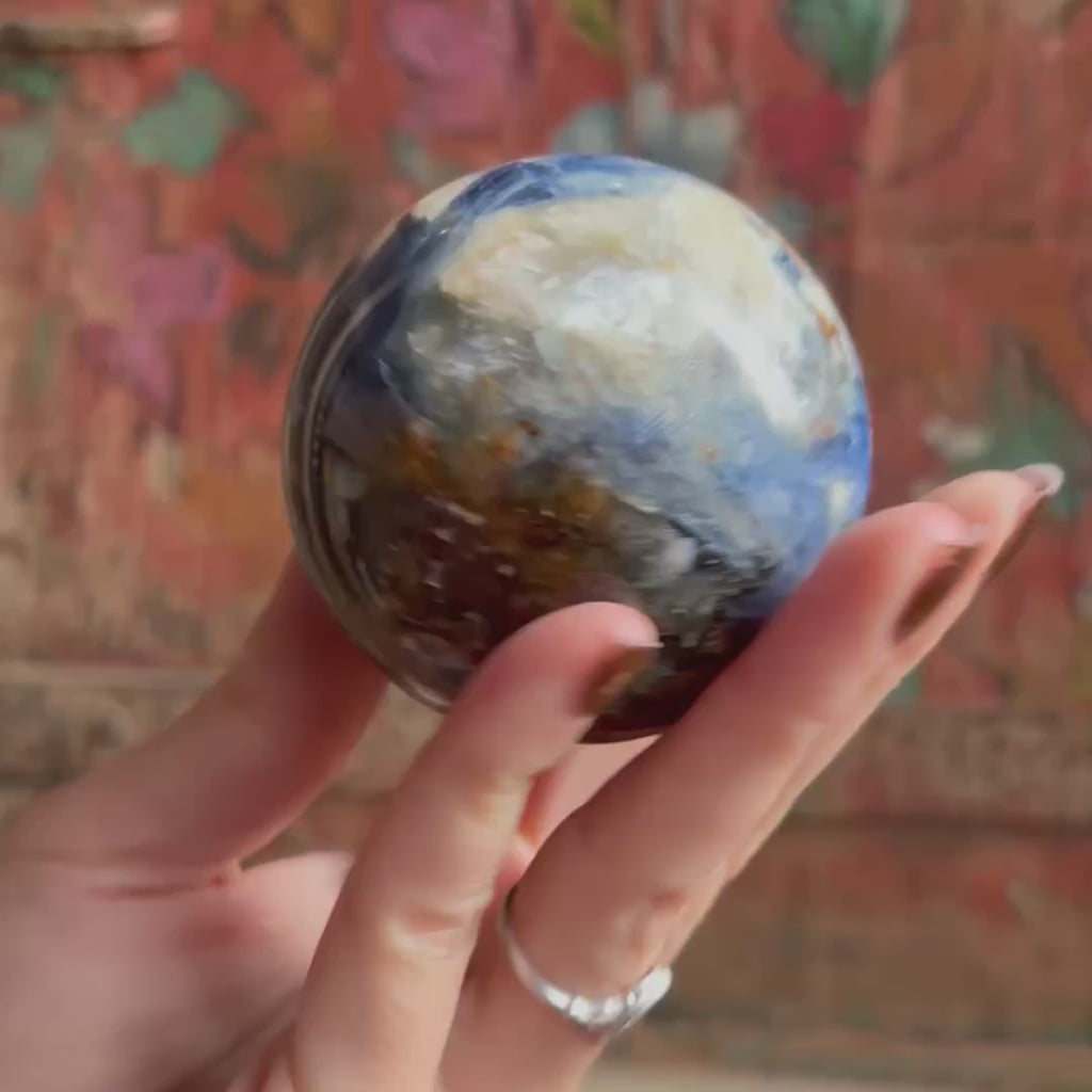 Hand holding a blue kyanite sphere showcasing the crystal