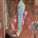 Blue Kyanite Crystal Scepter in hand in front of colorful door