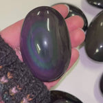 hand holding a rainbow palmstone and moving it around to shine light on it