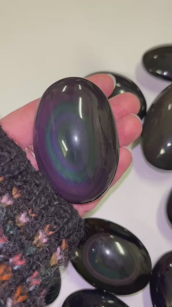 hand holding a rainbow palmstone and moving it around to shine light on it