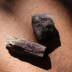 Two purple crystals on a brown surface