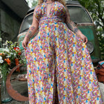 Person wearing a colorful floral jumpsuit standing in front of a vintage van.