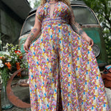 Person wearing a colorful floral jumpsuit standing in front of a vintage van.