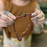 Person holding a beaded necklace with a blurred background