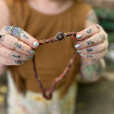 Person holding a beaded necklace with a blurred background