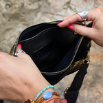 Someone holding the Small Black and Gold Heron Velvet Crossbody Bag open to show off the inside.