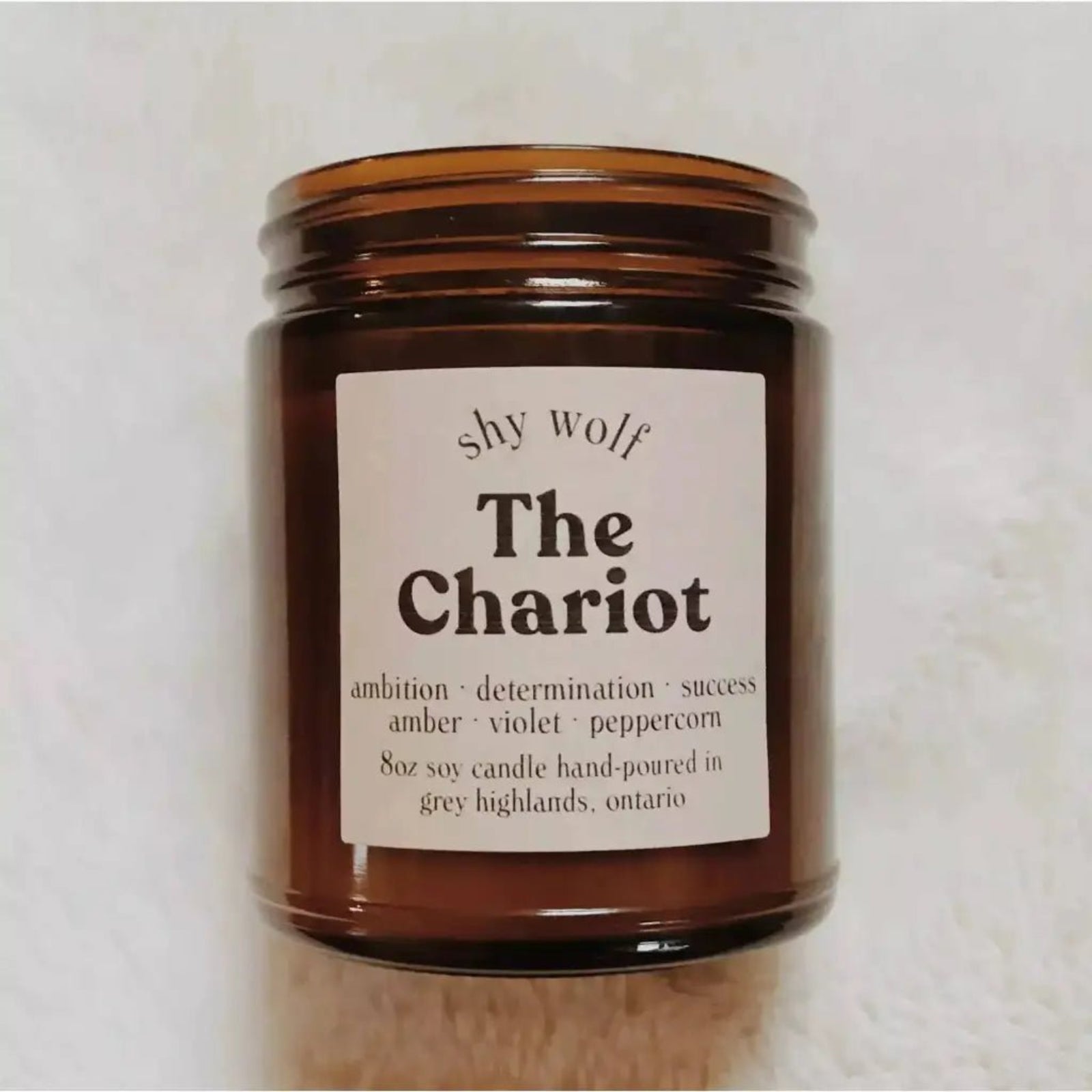 The Chariot candle on a white fluffy surface.