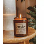 The Justice candle lit on a wooden surface.