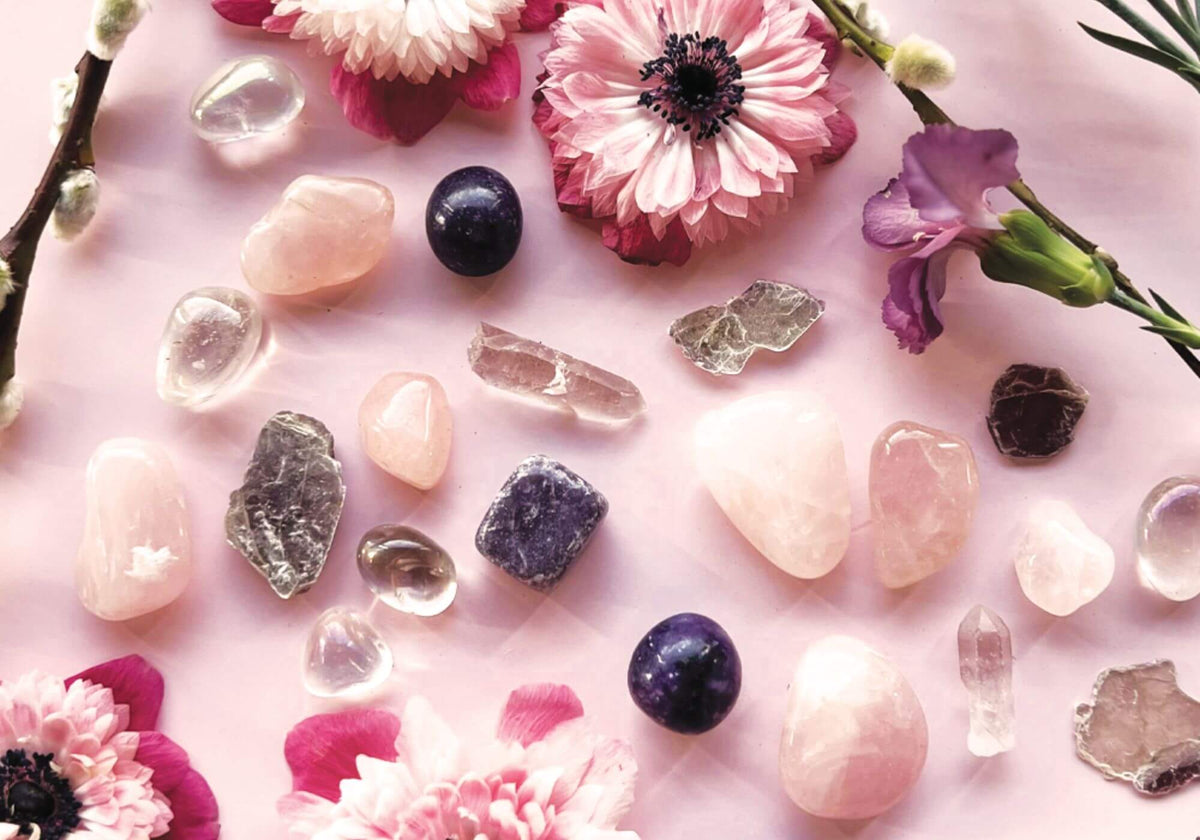 Crystals and flowers laid out on a pink background