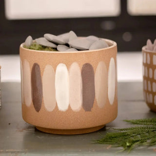 The Ceramic Planter with Paint Strokes on a gray surface with rocks in it.