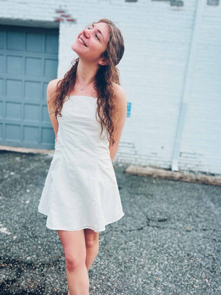 cute short mini dress boho festival style in front of white brick