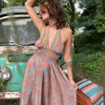 Woman in a floral dress standing next to a vintage van in a natural setting