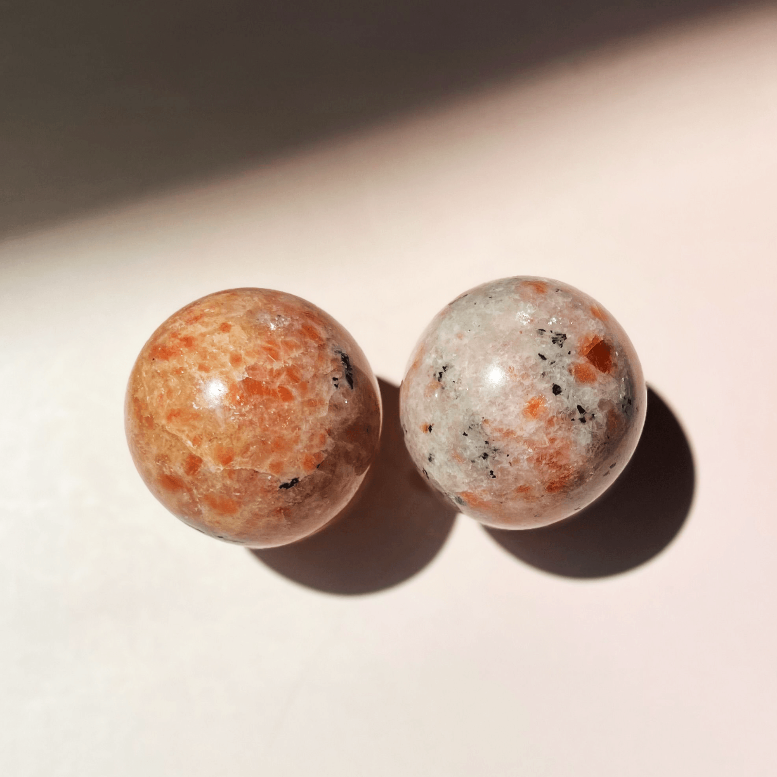 Two polished sunstone crystal spheres with orange and peach tones and natural sparkle