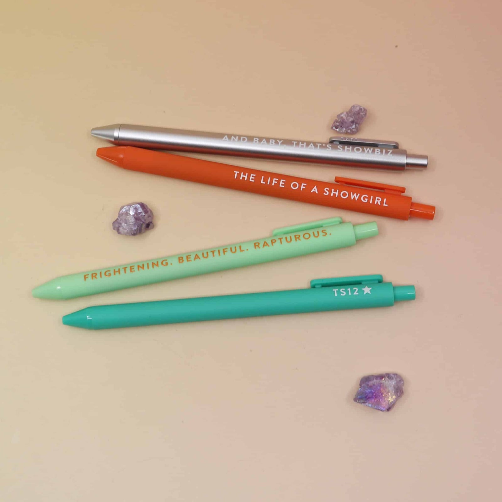 Four Taylor-inspired pens with phrases including The Life of a Showgirl, TS12, and And Baby That’s Showbiz.