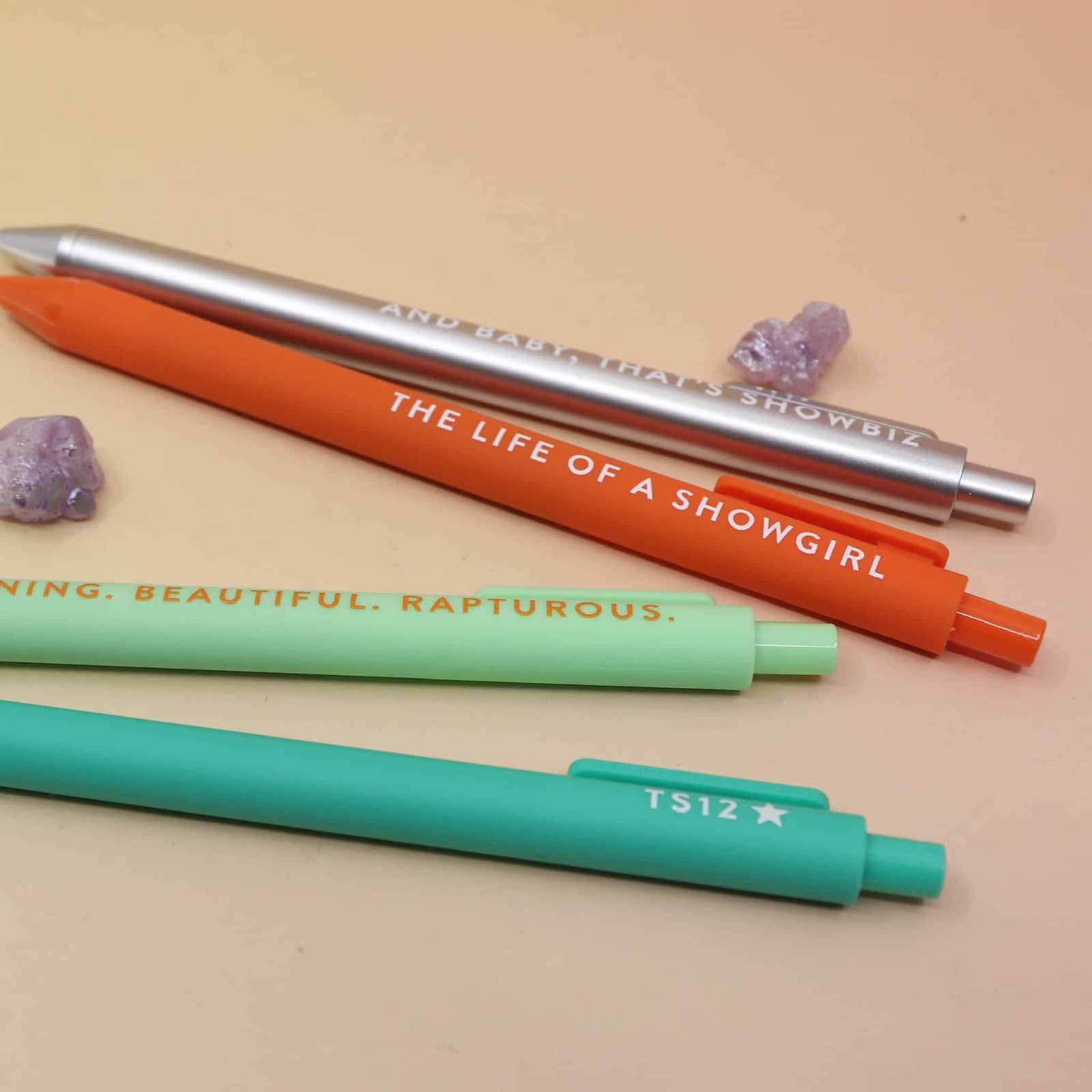Taylor Swift inspired Showgirl pen set with 4 colorful jotter pens displayed on pastel background.