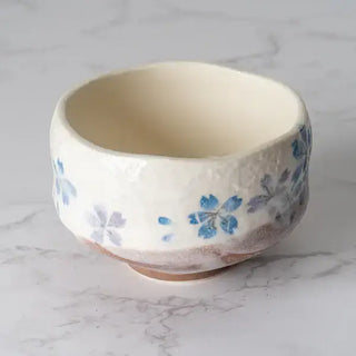 The Blue Sakura Cherry Blossoms Mini Matcha Bowl on a white marble background.