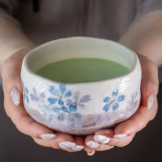 Someone holding the Blue Sakura Cherry Blossoms Mini Matcha Bowl with matcha in it.