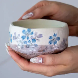 Someone holding the Blue Sakura Cherry Blossoms Mini Matcha Bowl on a white marble background.
