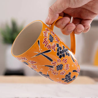 Someone holding the Yellow Flower Design Tea Mugs with Lid and Infuser on a white marble background.