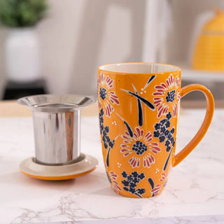 The Yellow Flower Design Tea Mugs with Lid and Infuser with the infuser being shown on a white marble background.