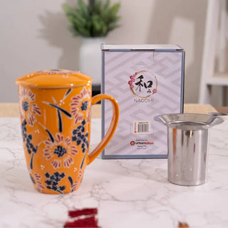 The Yellow Flower Design Tea Mugs with Lid and Infuser with the infuser being shown and its packaging on a white marble background.