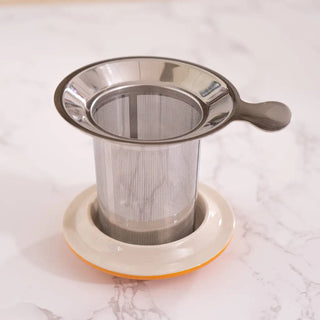 The Yellow Flower Design Tea Mug infuser and lid on a white marble background.