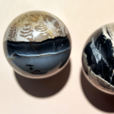 UV reactive volcano agate crystal sphere glowing under blacklight with natural black and cream banding