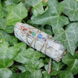 Sage bundle with colorful stones tied with twine on green leaves