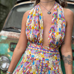 Woman wearing a colorful patterned dress with a vintage vehicle in the background